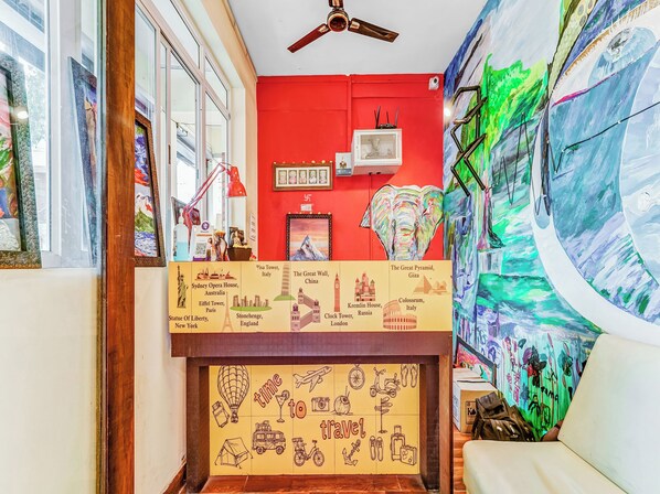 Una habitación con una pared roja, un ventilador de techo y un mural de un globo aerostático.