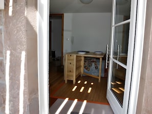 Ein Zimmer mit einem Holztisch, einem Stuhl, einem kleinen Teppich und einer Schiebetür aus Glas.