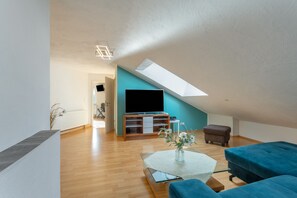 Un salon moderne avec un téléviseur à écran plat, une table basse et un canapé.