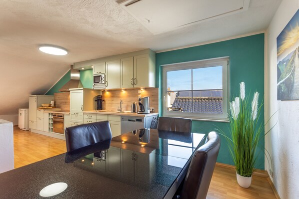 Una cocina moderna con comedor, vistas a paneles solares y una planta en maceta.