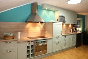 A kitchen with a built-in oven, microwave, and stove, wooden countertop, and light-colored cabinets.