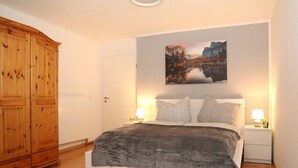 Ein Schlafzimmer mit einem Bett, zwei Nachttischen mit Lampen, einem Holzschrank und einem Bild an der Wand.