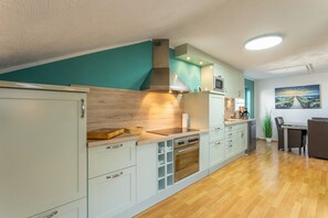 A modern kitchen with a wooden countertop, stainless steel appliances, and teal walls. - Vogler Holiday Apartment (Herscheid)