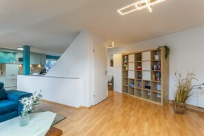 A modern living room with a blue sofa, a glass coffee table, and a bookshelf. - Vogler Holiday Apartment (Herscheid)