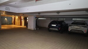 Un espace de stationnement avec deux voitures, un panneau indiquant le parking de l’hôpital Matrix, et l’entrée d’un hôtel.