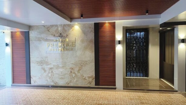 Un hall d’hôtel avec un mur en marbre, des lambris en bois et un ascenseur en verre.
