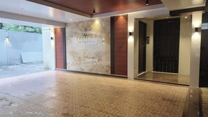 Un hall d’hôtel avec un mur en marbre, un comptoir d’accueil et un ascenseur.