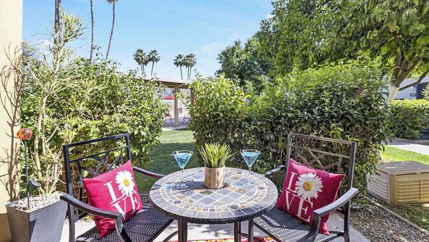 An outdoor patio with two chairs, a round table, and a potted plant. - Fashion Square Townhouse | 4 Heated Pools (Scottsdale)