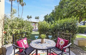 An outdoor patio with two chairs, a round table, and a potted plant. - Fashion Square Townhouse | 4 Heated Pools (Scottsdale)