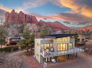 A modern two-story house with a balcony, surrounded by trees and red rock formations. - NEW|Moondance Redrock View Terrace|Mtn. Views (Sedona)