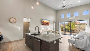 Una cocina moderna con una isla central, un área de comedor con un sofá blanco y un amplio ventanal con vistas al exterior.