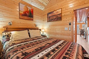 Puupaneeliseinäinen huone, jossa on sänky, taulu, lamppu ja seinäkello.