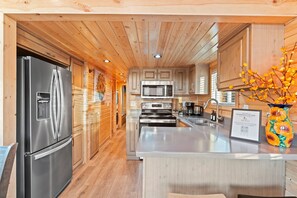 Una cocina moderna con electrodomésticos de acero inoxidable, armarios de madera y una isla central.