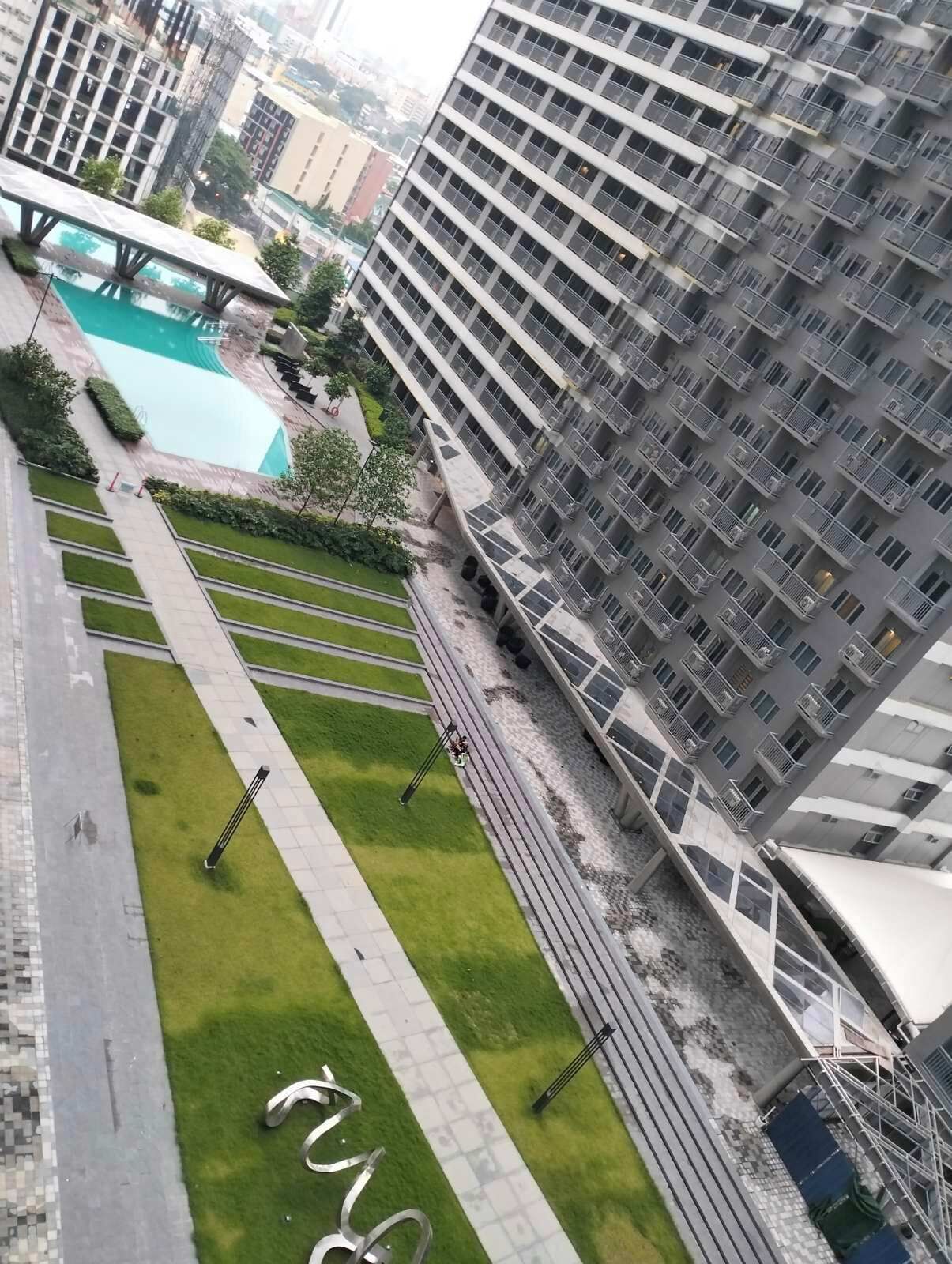 A high-rise building with a rooftop pool and a well-maintained lawn with pathways.