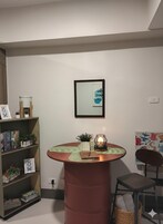 A room with a round wooden table, a bookshelf, a framed picture, and a chair.