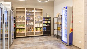 A grocery store interior with refrigerated sections, shelves stocked with various products, and a blue-lit beverage refrigerator.