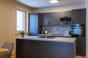 Una cocina moderna con una isla central, electrodomésticos integrados y un ventanal que proporciona luz natural.