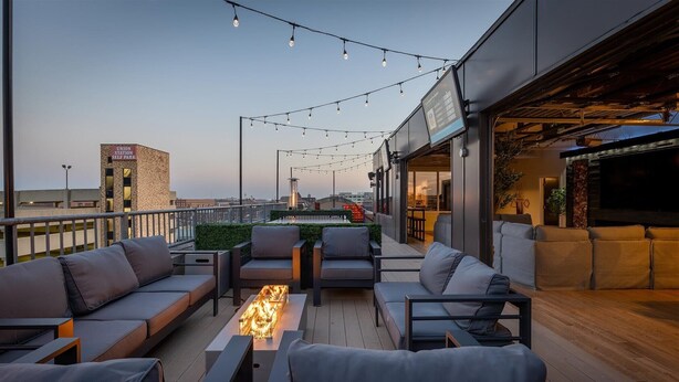 A rooftop terrace with outdoor seating, a fire feature, and string lights. - Penthouse of all Penthouses (Indianapolis)