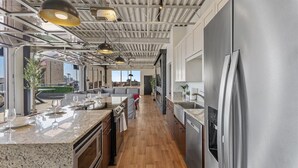 A modern kitchen with a large island, stainless steel appliances, and a view to the outside. - Penthouse of all Penthouses (Indianapolis)
