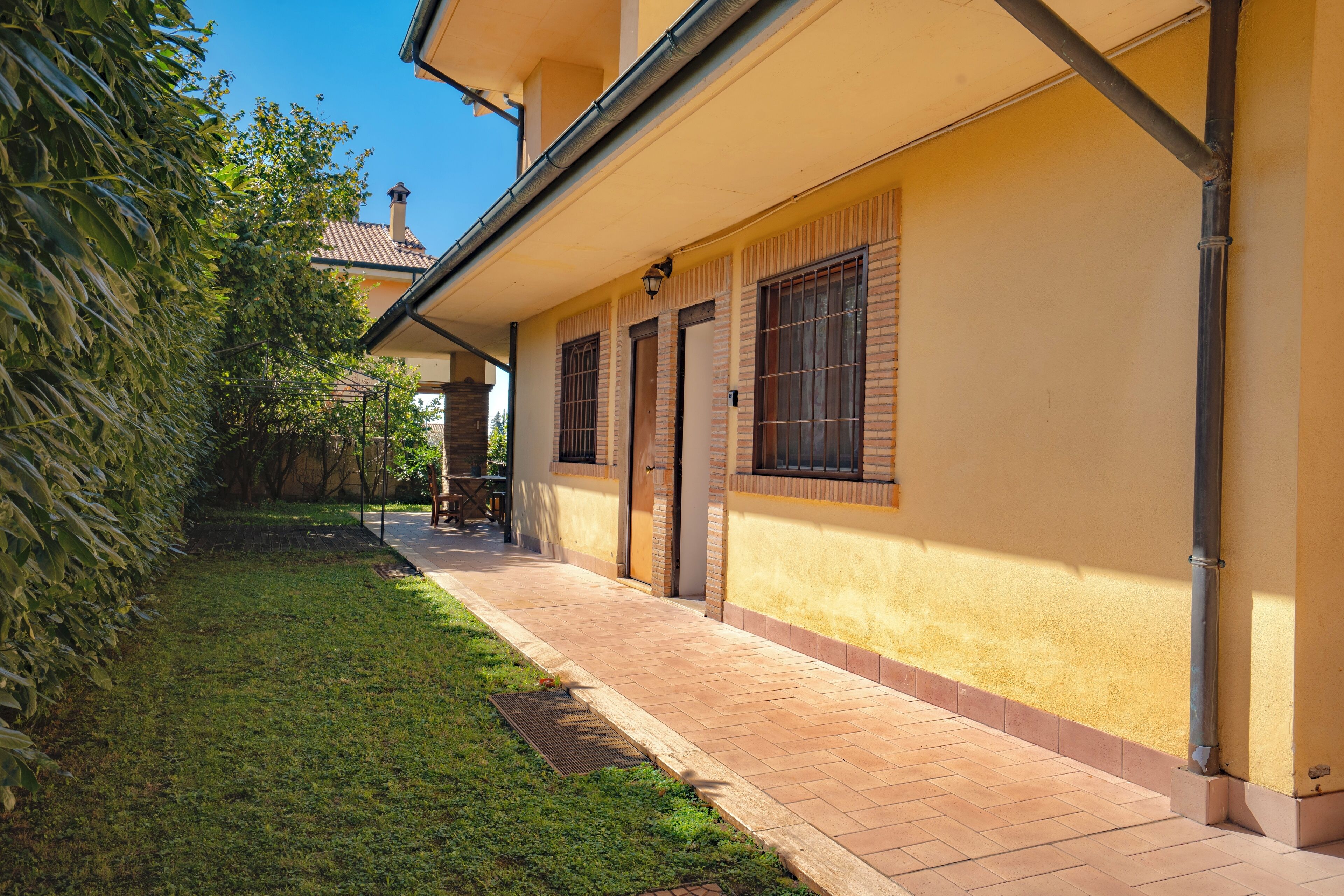 A yellow building with a covered patio, a small garden, and a visible chimney.