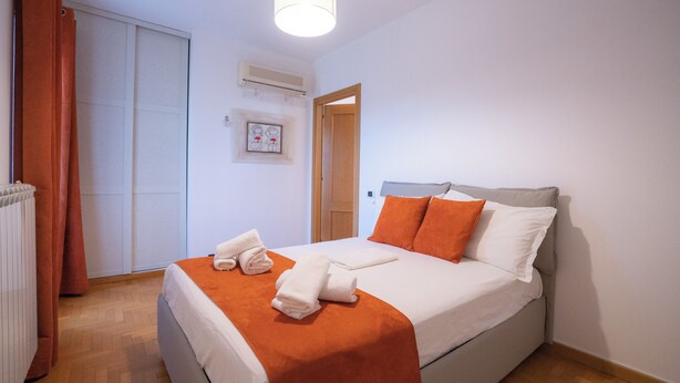 Una habitación de hotel con una cama, un radiador, una puerta y una lámpara.