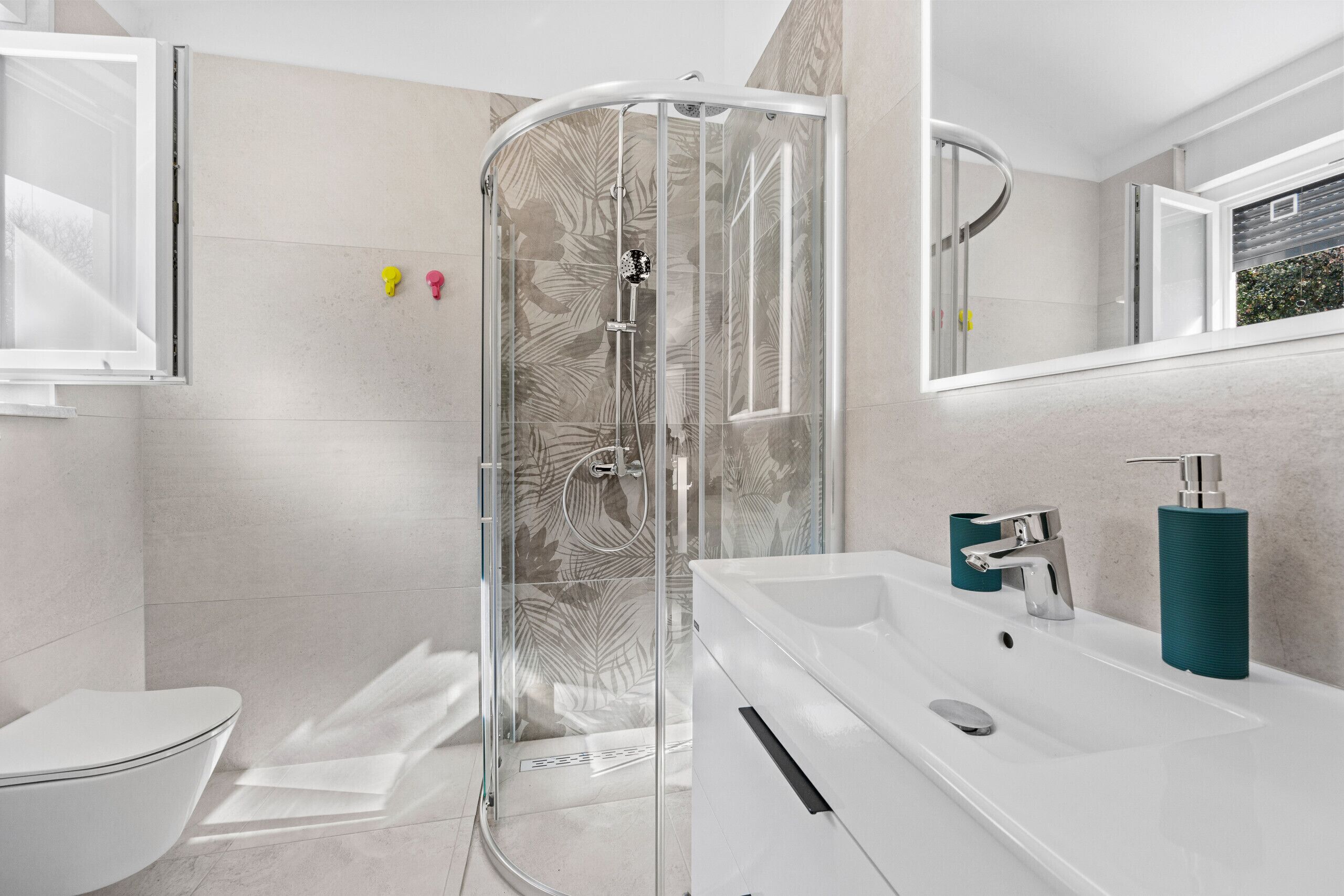 A modern bathroom with a glass shower enclosure, a white sink, and a toilet.