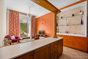 A kitchen with a large island, wooden cabinets, a dining area with a table and chairs, and a window with a view of greenery. - Seaside Family Apartment Una - Sunny Rab Island (Rab)