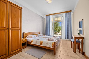 A bedroom with a bed, wooden wardrobe, bedside table, and a view through a window. - Seaside Family Apartment Una - Sunny Rab Island (Rab)