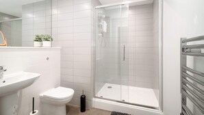 A modern bathroom with a glass-enclosed shower, a white sink, and a toilet. - Modern Studio Apartment in Waterloo, Liverpool (Liverpool)