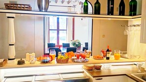 A breakfast bar with a variety of food and drinks, including fruits, juices, and wine bottles.