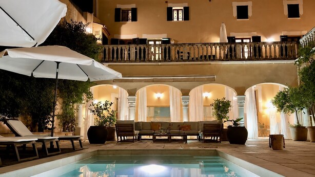 An outdoor pool area with lounge chairs, umbrellas, and a seating area with tables.