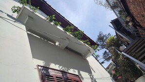 Rakennuksessa on valkoinen julkisivu, punainen ikkuna ja kasveilla koristeltu parveke.