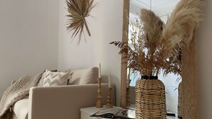 A minimalist living room with a sofa, a white console table, and a large mirror reflecting a window.