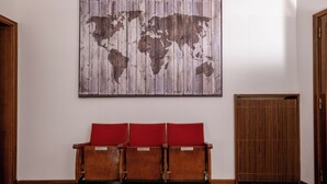 A room with a wooden bench with red cushions, a world map on the wall, and a wooden door. - Room & Breakfast D'Annunzio (Ravenna)