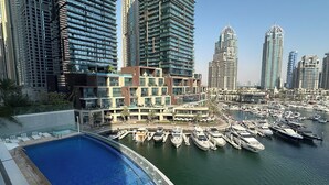 A marina with yachts docked, surrounded by high-rise buildings and a swimming pool area. - Maison Privee - Sleek Stay in Dubai Marina’s Famous Twisting Tower  (Dubai)