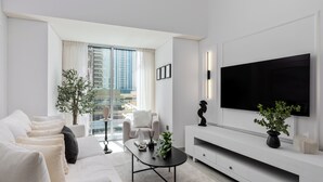 A modern living room with a sofa, coffee table, and TV. - Maison Privee - Sleek Stay in Dubai Marina’s Famous Twisting Tower  (Dubai)