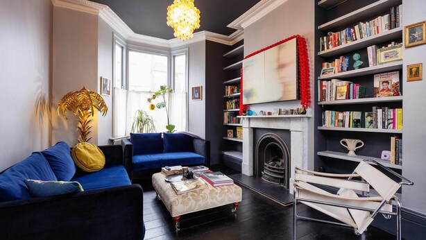A modern living room with a blue sofa, a small table, a bookshelf, and a fireplace.