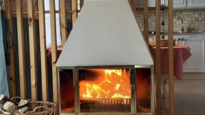 Un salon moderne avec une cheminée, un lambris en bois, un panier en osier et un canapé.