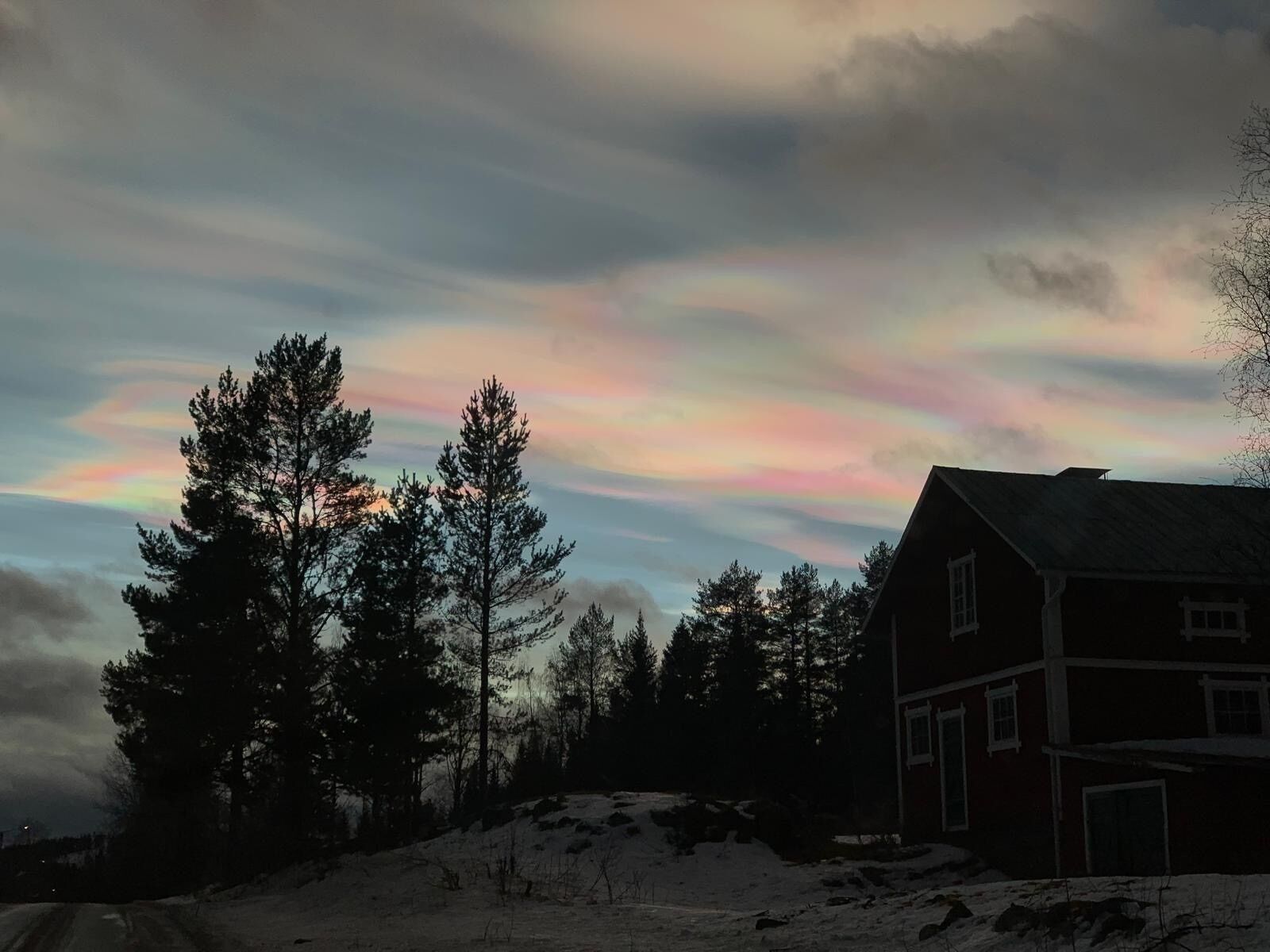Una casa con techo inclinado, rodeada de árboles y nieve.