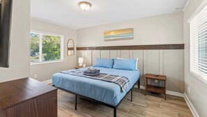 Un dormitorio con cama, mesita de noche y ventana con persianas.
