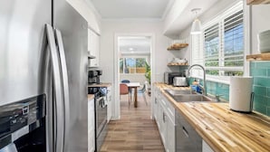 Cocina moderna con electrodomésticos de acero inoxidable, encimeras de madera y vistas al área de comedor.