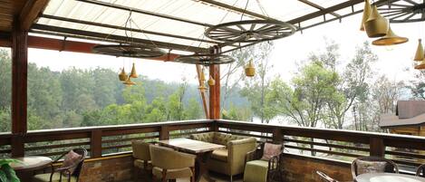 A wooden deck with a table and chairs, overlooking a forested area.