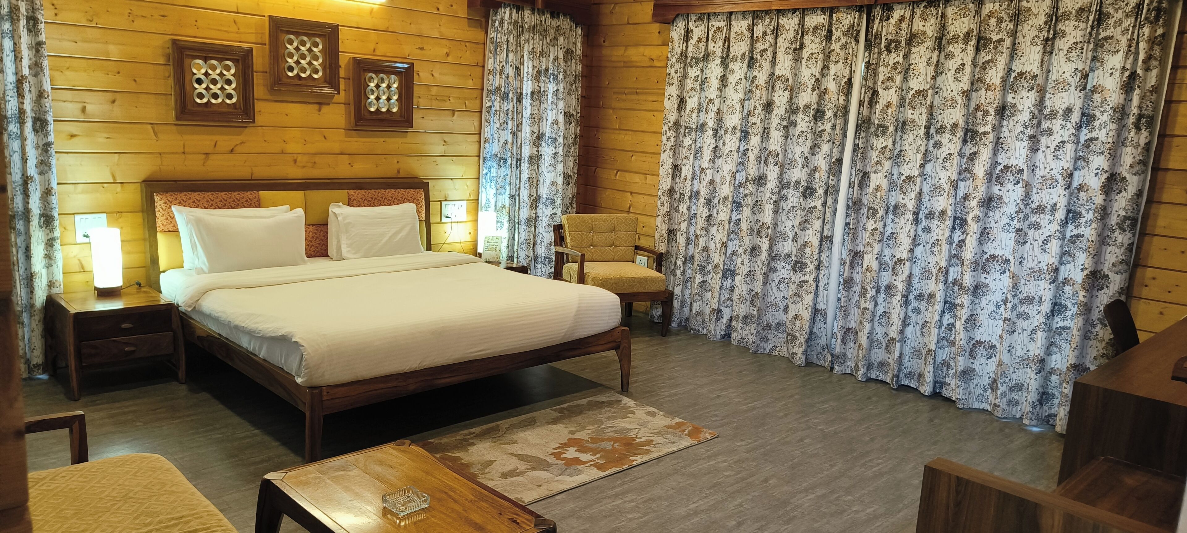 A wooden room with a bed, nightstands, a chair, and curtains.