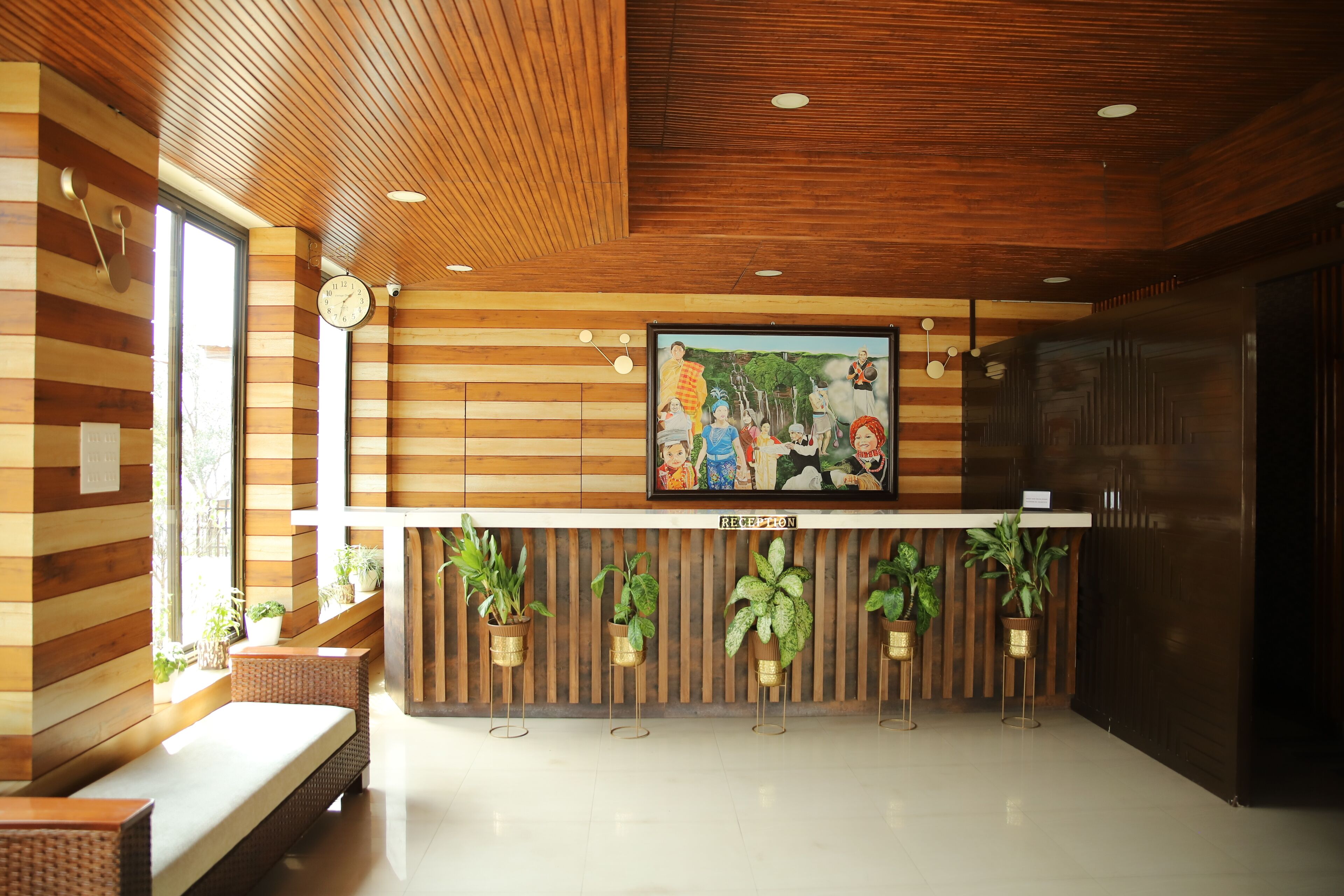 A reception area with wooden paneling, a clock, a framed mural, and potted plants.