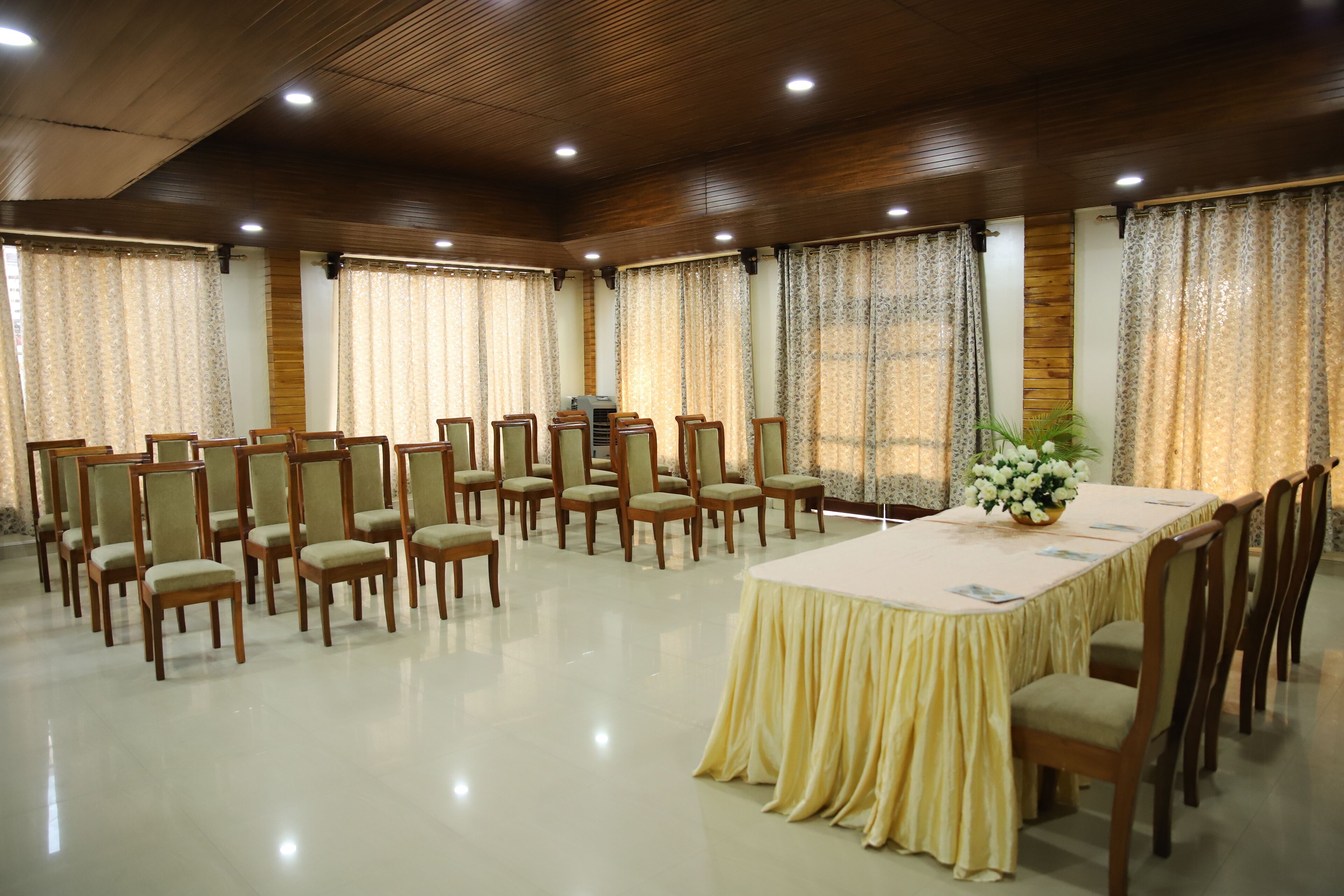 A conference room with a long table, chairs, and curtains.