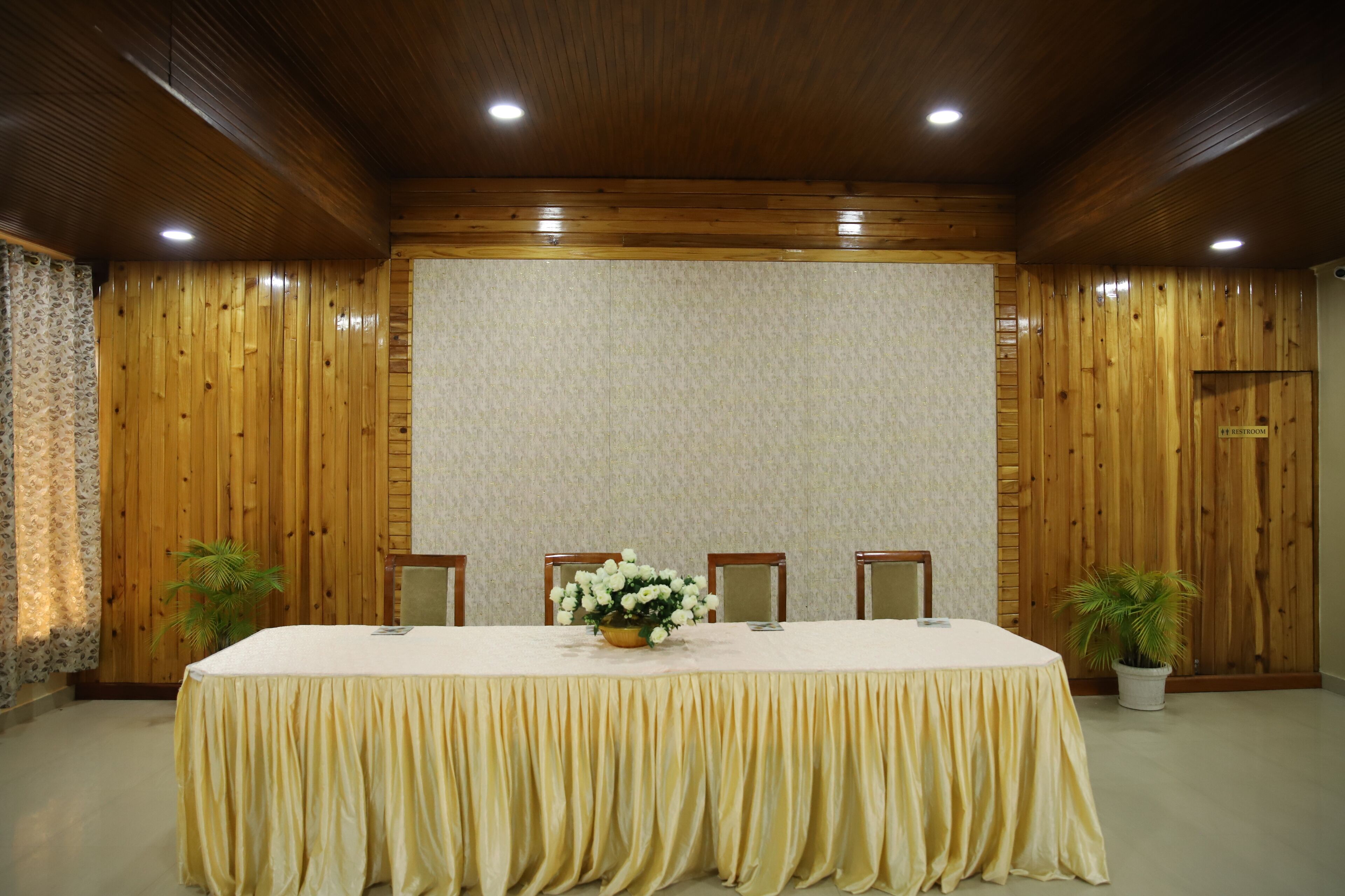 Une salle de conférence avec une longue table, quatre chaises et un arrangement floral au centre.