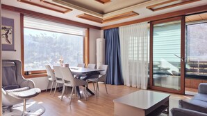 Un salon moderne avec un coin repas, de grandes fenêtres et une vue sur l’extérieur.
