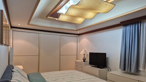 Une chambre à coucher avec un lit, une télévision, une lampe et une commode.