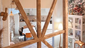 A modern kitchen with wooden beams, a dining area with orange chairs, and a white cabinet with glass doors.