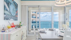 A dining area with a view of the ocean, a large window, and a table set for two.